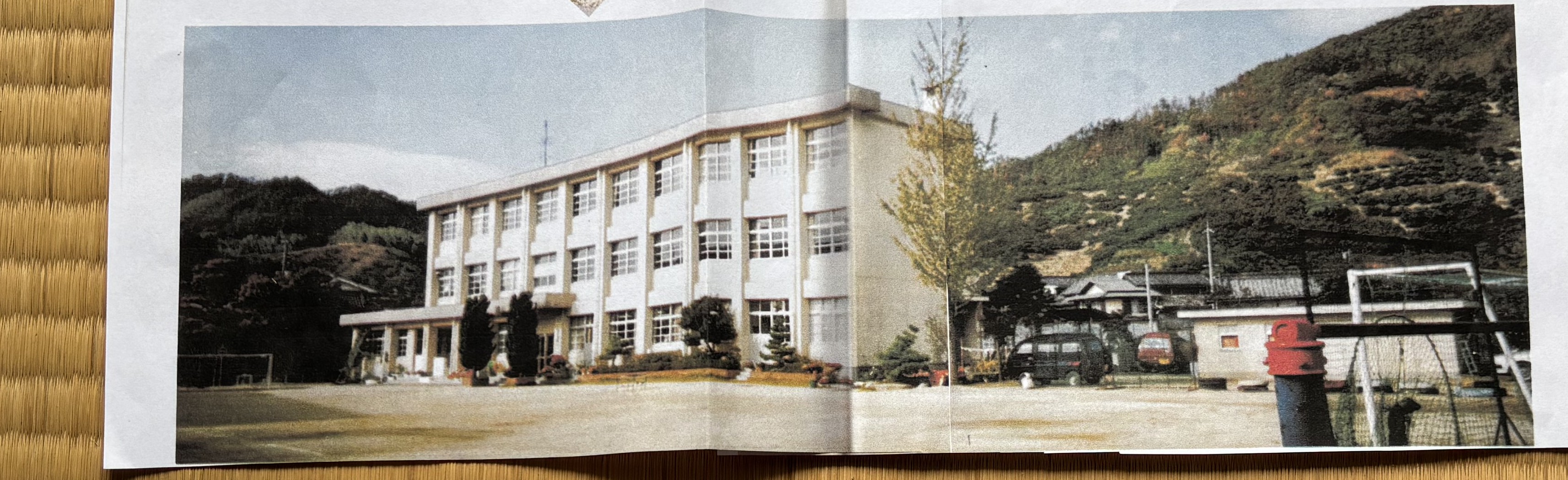 A school building from a 学園風景 ("campus scenery") booklet, shared by a Sunoue resident at the morning Radio Taiso on 2026-06-04; said to date from the last year Sunoue Elementary was open / 「学園風景」と題された冊子の校舎。2026年6月4日の朝のラジオ体操で須ノ上の住民が提供。須ノ上小学校が開いていた最後の年のものという。
