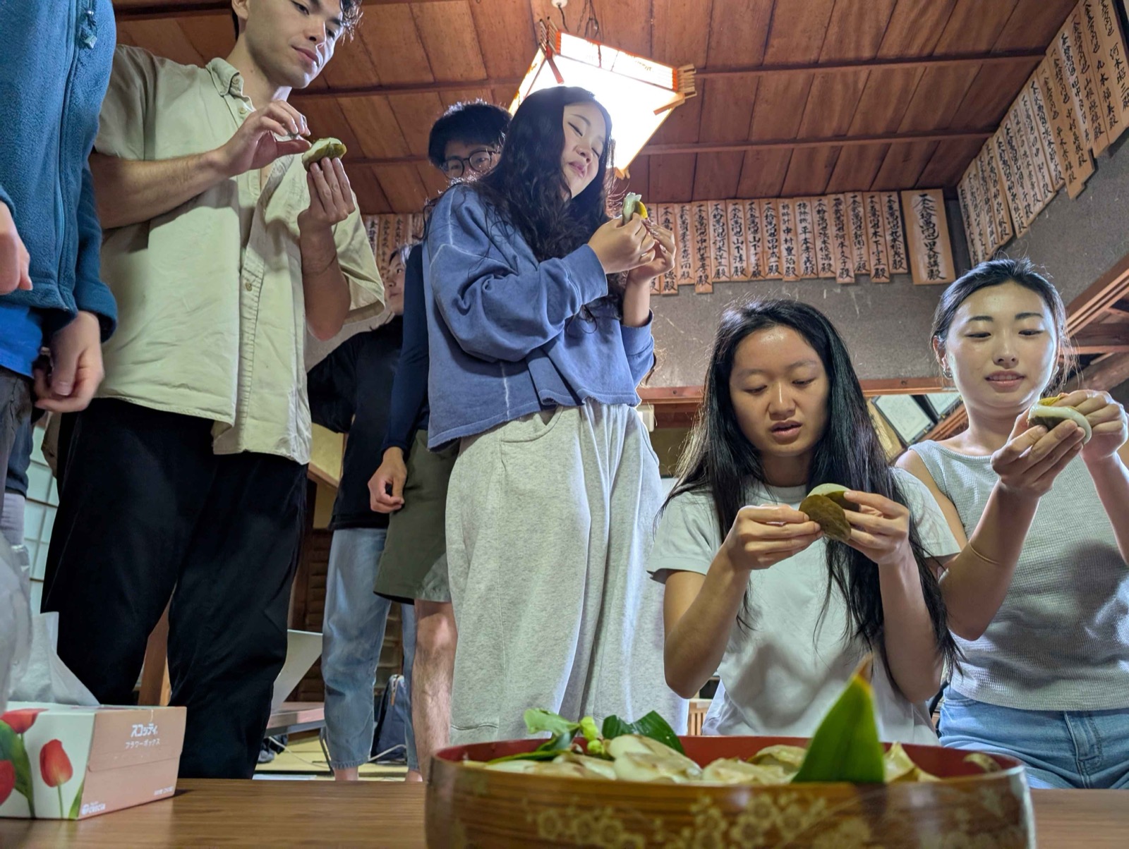 Members of the cohort peeling the leaves and tasting the mochi at Kakumeisha. 格明舎で学生たちが葉をはがして柏餅を味わう。