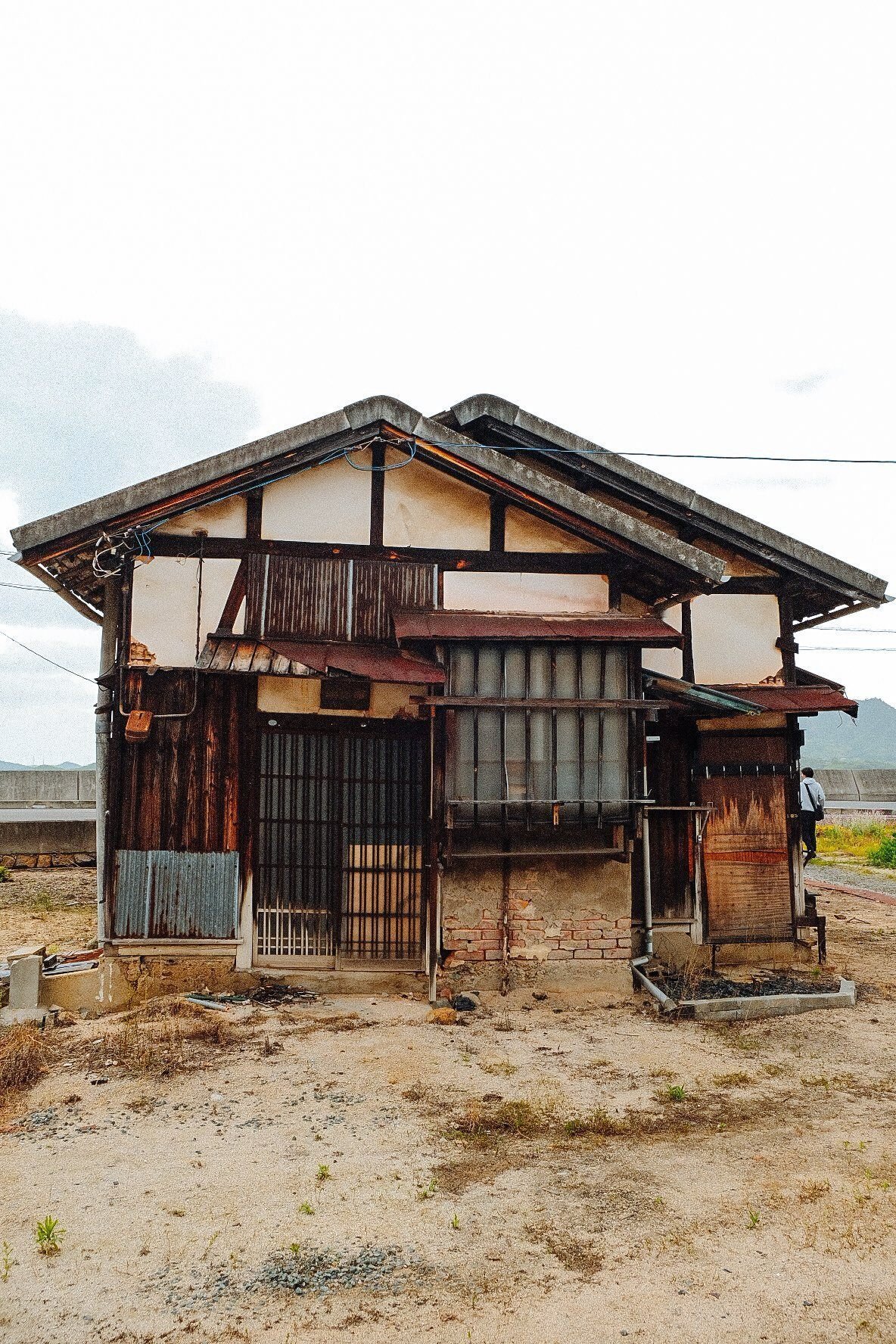 A vacant island house, the former municipal housing the Workshop has been deconstructing: weathered timber, mud-plaster walls, corrugated patches / 解体を進めてきた島内の旧市営住宅、風化した木部と土壁