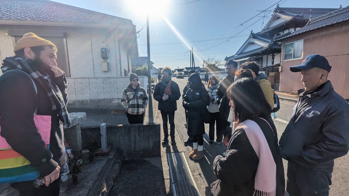 A vacant-houses walking tour on the island: students and staff with an islander on a Sunoue street / 島内の空き家ツアー、須ノ上の通りにて学生・スタッフと島民