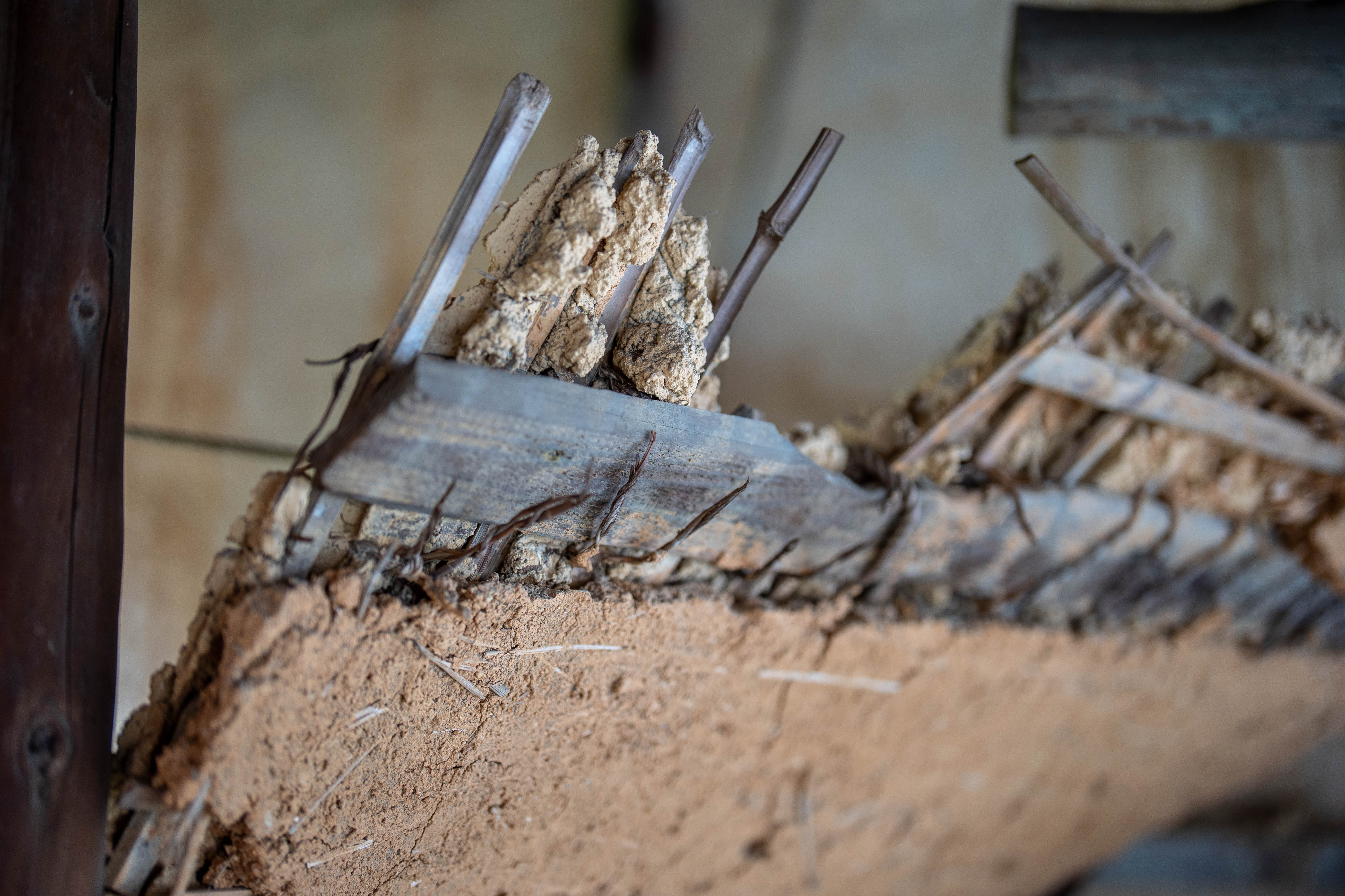 A cross-section of a deconstructed earthen wall (tsuchikabe), the bamboo lath (komai) and straw-clay layers exposed where the wall has been cut. 解体された土壁の断面。切り口から、竹の小舞と藁を含んだ土の層があらわになっている。